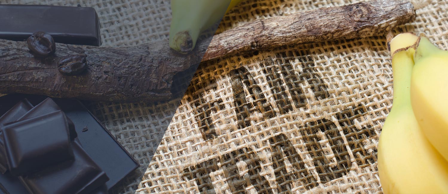 Dunkle Schokoladenstücke mit Kaffeebohnen, Bananen und natürlichem Holz auf Jutehintergrund.