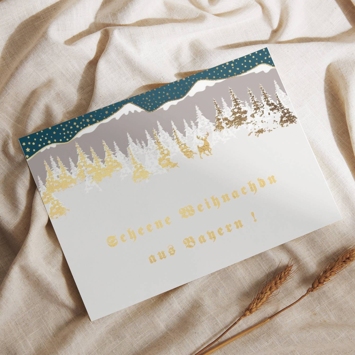 Glückwunschkarte „Scheene Weihnachdn“ mit Winterlandschaft inkl. Bergen, Tannen und Reh. Goldene Prägung.