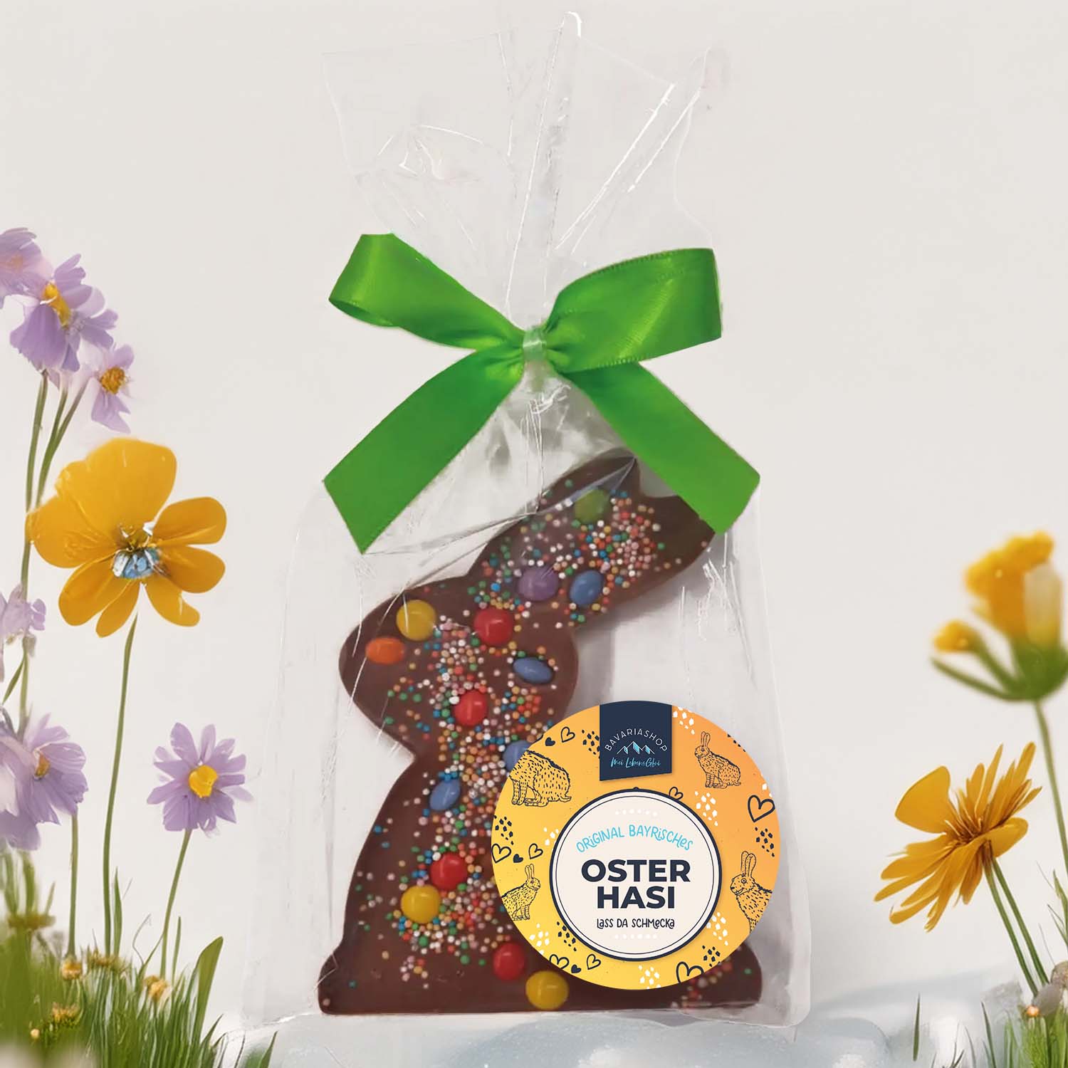 Oster-Schokoladen "Schokolinsen-Haserl" mit bunten Schokolinsen, Zuckerstreuseln und grünem Band in Geschenkfolie.