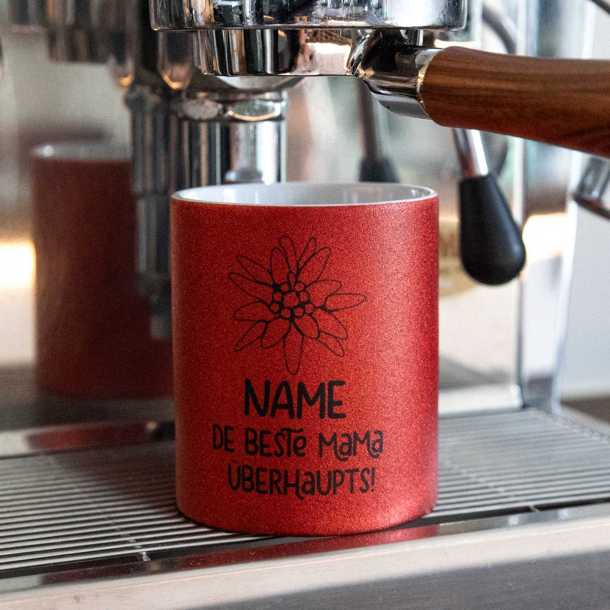 Rot glitzerndes Kaffee Haferl "De beste Mama überhaupts" personalisiert mit Edelweiss-Motiv in Siebträgermaschine