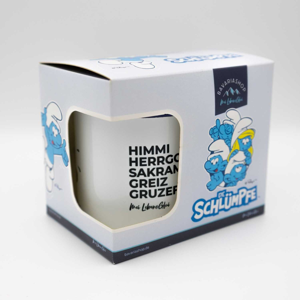 Schlümpfe Tasse Himme Herrgott in weißer Geschenkverpackung mit Abbildung mehrerer Schlümpfe und Schriftzug.