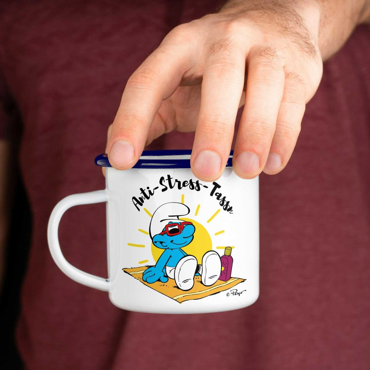 Weiße Schlümpfe Emailletasse Anti Stress Herren mit Comic Schlumpf im Liegestuhl und Sonnenbrille, gehalten von Hand.