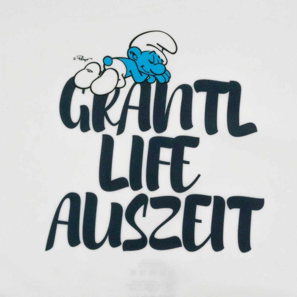 Die Schlümpfe Grantl Life Auszeit Kuschelkissen Motiv mit schlafendem Schlumpf auf Schriftzug.