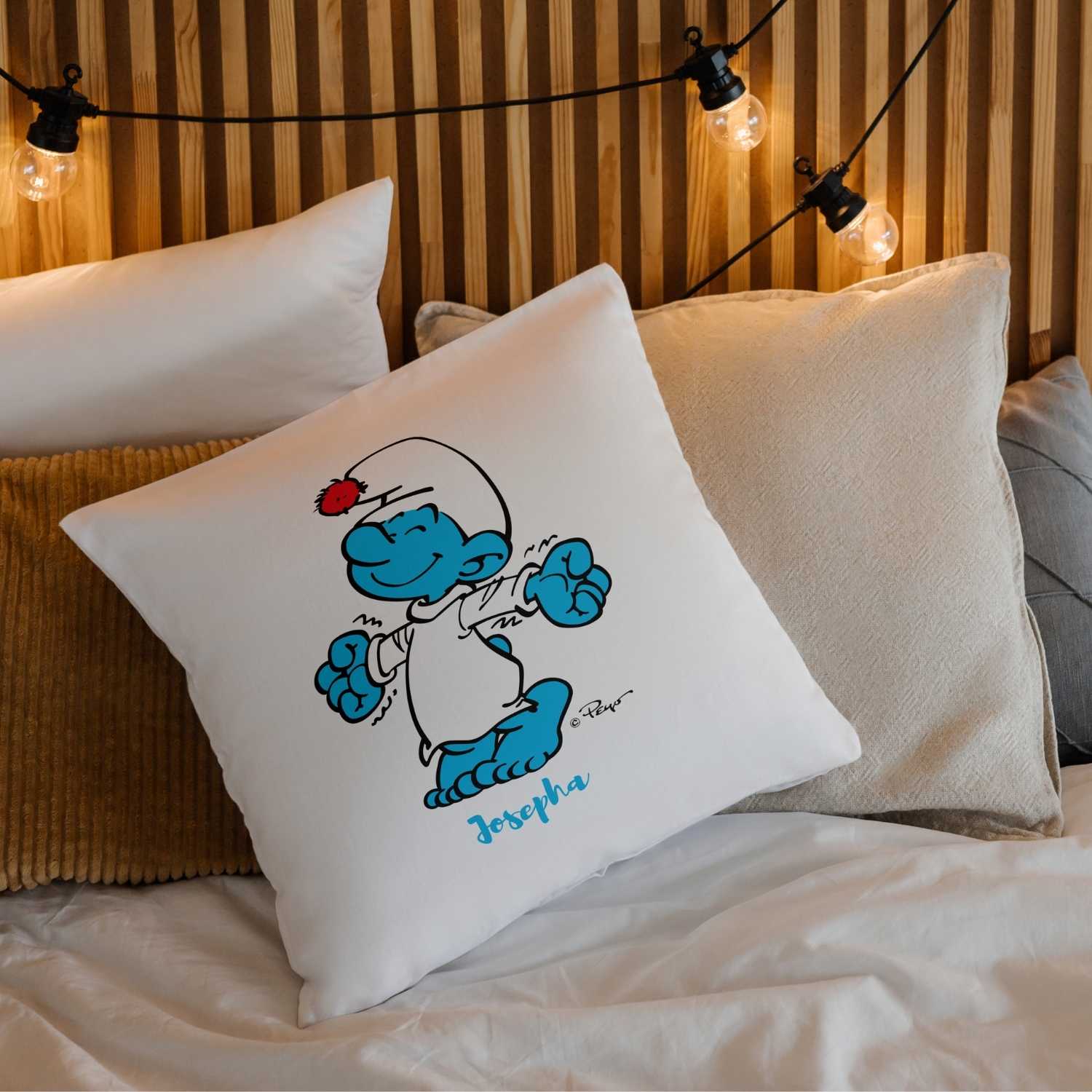 ®Die Schlümpfe Schlaf guad Kuschelkissen personalisiert mit Schlumpf im Schlafanzug auf Bett, Holzkopfteil und Lichterkette.