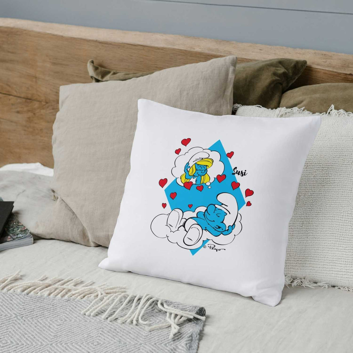 Weißes Schlümpfe Träume Kuschelkissen personalisiert mit schlafendem Schlumpf, Schlumpfine und roten Herzen auf Bett.