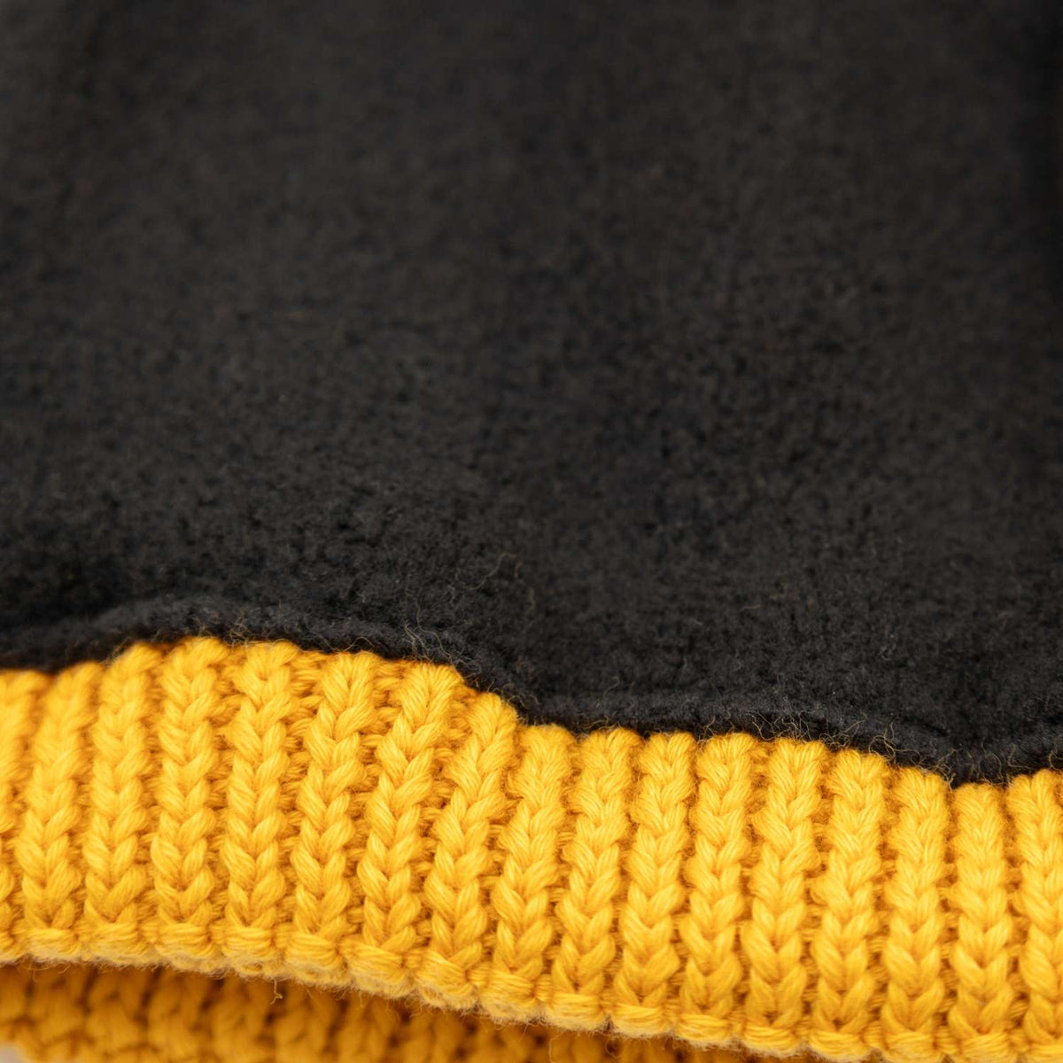 Nahaufnahme der schwarzen Pumuckl Beanie aus Baumwolle mit Rippstrick-Bund und warmem Fleecefutter innen