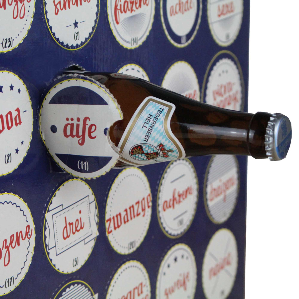 Tegernseer Hell Flasche mit blau-weißem Etikett in dekorativem Wandhalter oder Bild.