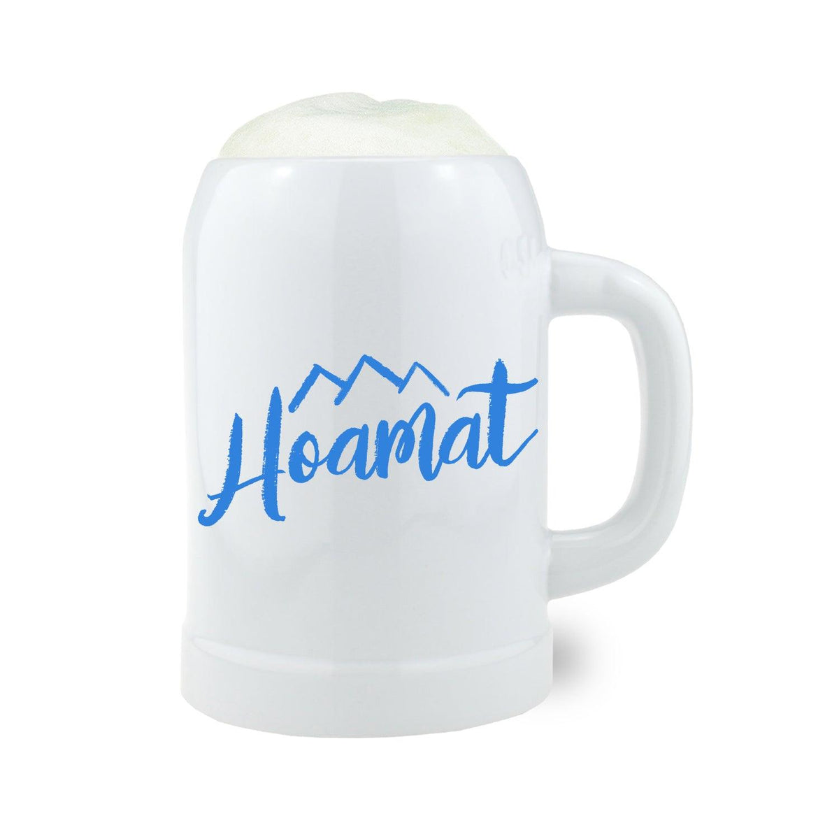 Weißer Bierkrug Hoamat mit blauem Schriftzug und Bergmotiv, gefüllt mit Schaum.