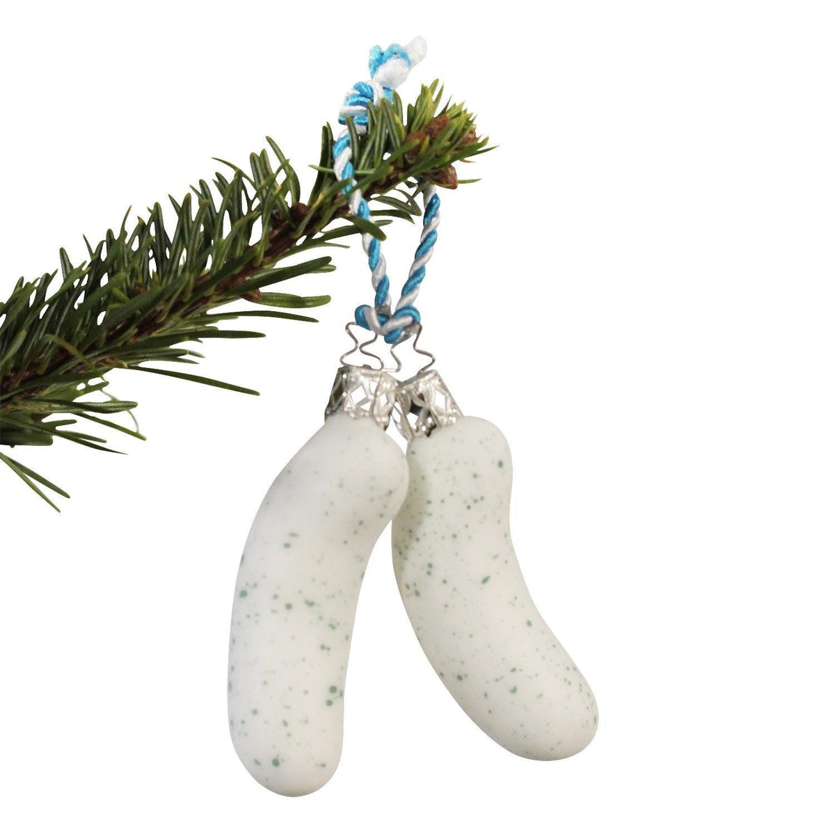 Zwei weiße Weisswurst-Christbaumkugeln mit grünen Sprenkeln hängen an einem Fichtenzweig vor weißem Hintergrund.