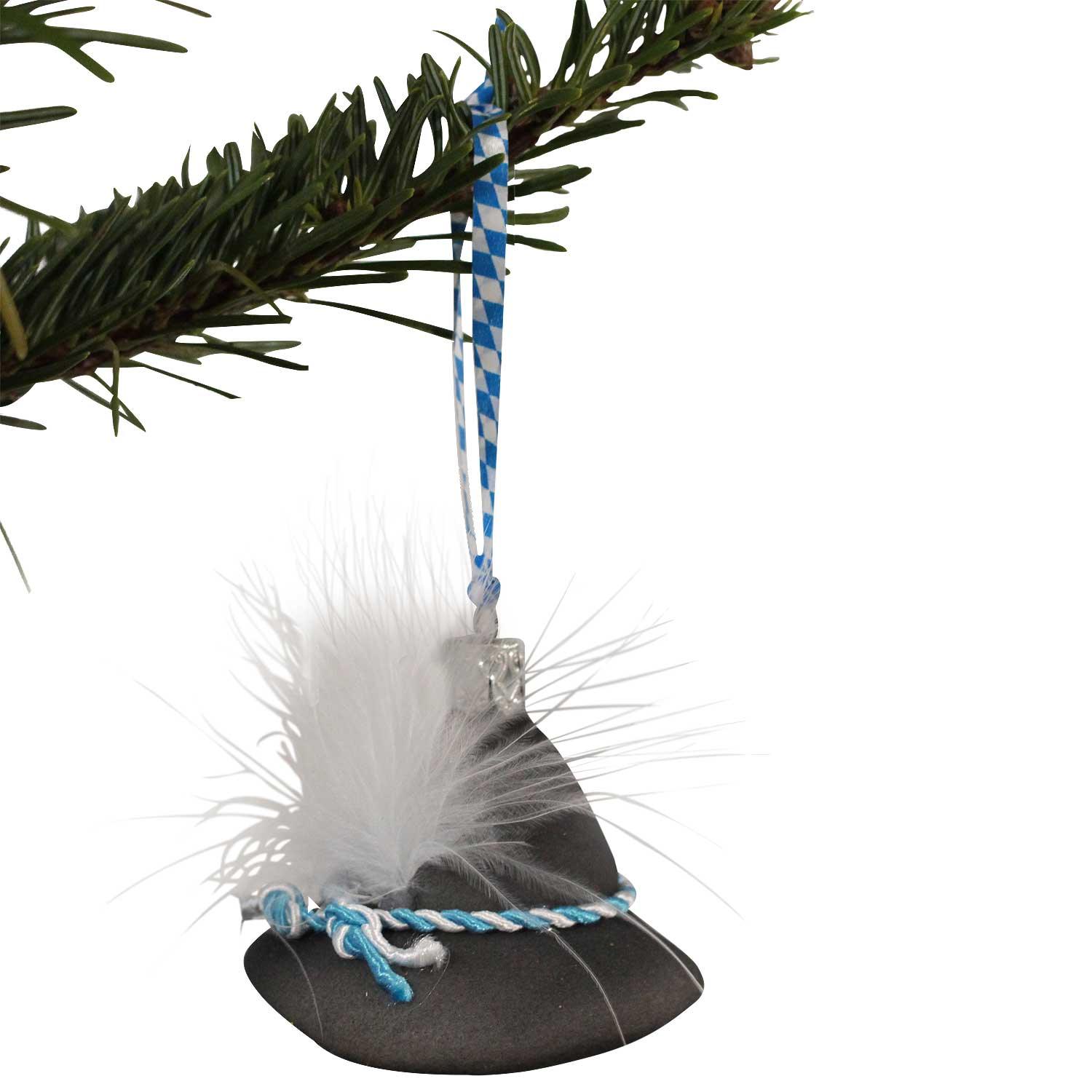 Bayerischer Trachtenhut Christbaumschmuck mit weißer Feder und blau-weißem Band hängt am grünen Zweig