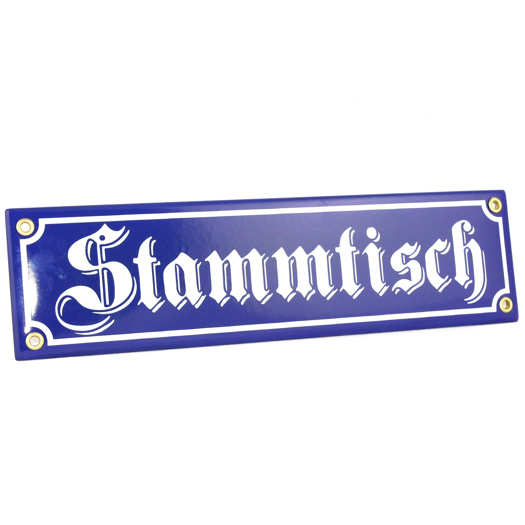 Blaues Emailleschild mit weißer Schrift "Stammtisch" in Fraktur und vier Befestigungslöchern.