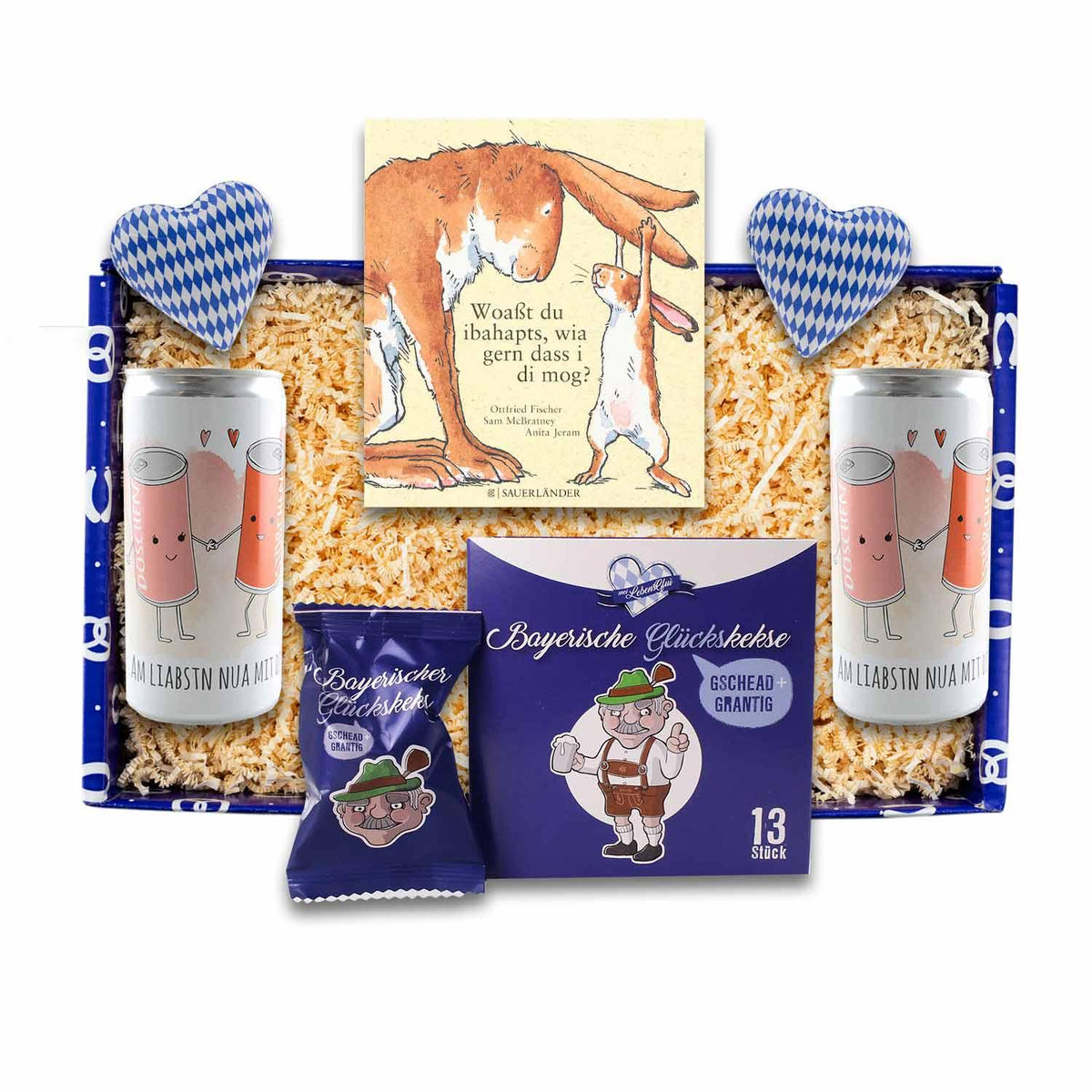 Geschenkbox Zua Hochzeit mit Buch, Glückskeksen, Bierdosen und blau-weißen Herzen auf Holzwolle.