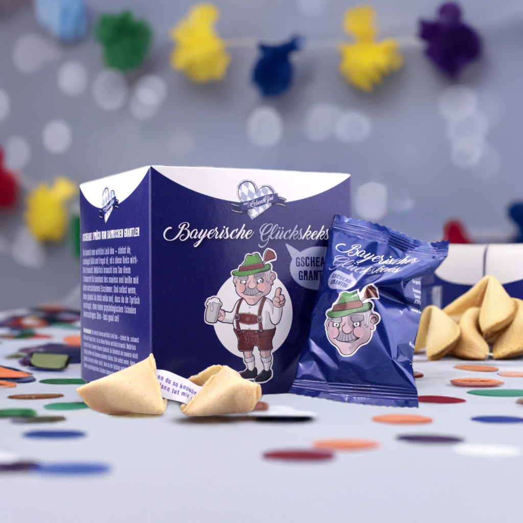 Bayerische Glückskekse Grantlerkekse in blauer Verpackung auf Tisch mit Konfetti und Girlande.