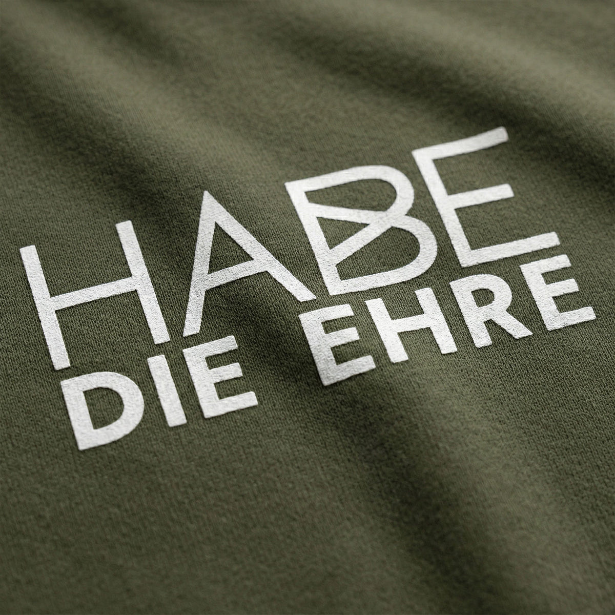 Grüner Hoodie mit weißem Aufdruck "HABE DIE EHRE" und feiner Stoffstruktur, sichtbare Falten des Stoffes