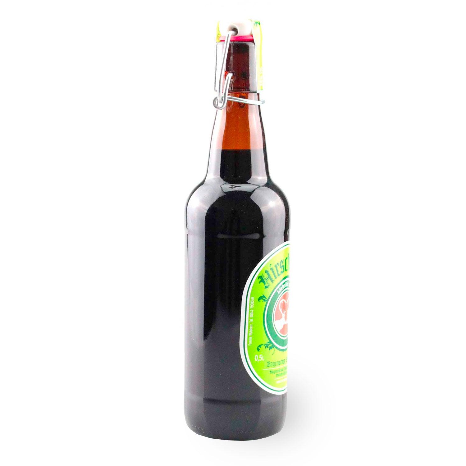 Dunkle 0,5l Flasche mit Bügelverschluss, grünem Etikett mit hellem Hirschlogo und Kräuterdarstellung