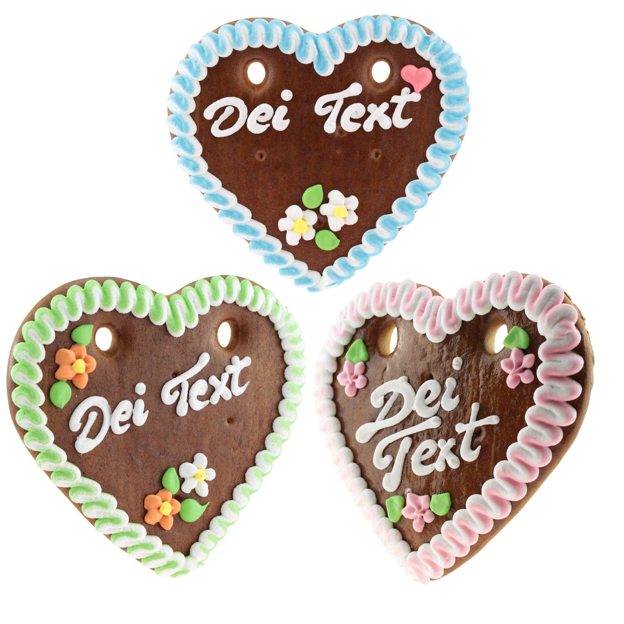 Drei personalisierbare Lebkuchenherzen mit bunter Zuckerglasur, Blumenmotiven und individualisierbarer Aufschrift.