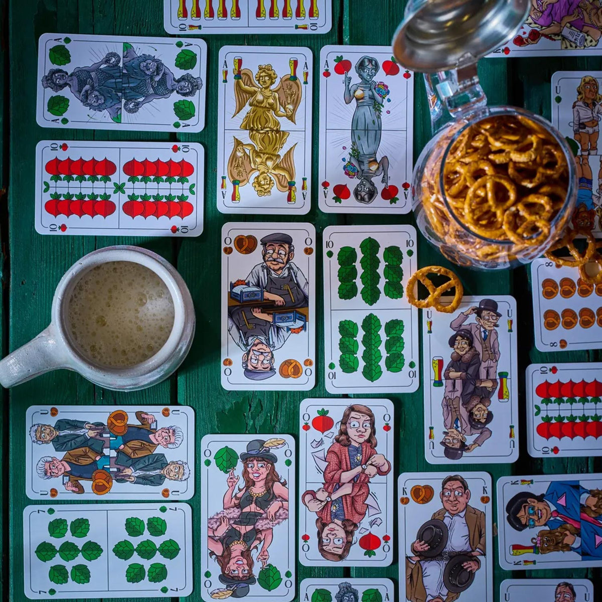Ausgebreitete Münchner Schafkopf Karten auf Holzplatte mit Bierkrug und Brezeln, perfekt für einen Spieleabend.