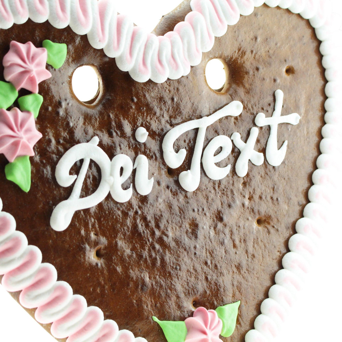 Braunes Lebkuchenherz mit weißer Zuckerguss-Randverzierung, rosa Blumen und Beschriftung Dein Text auf Glasur.