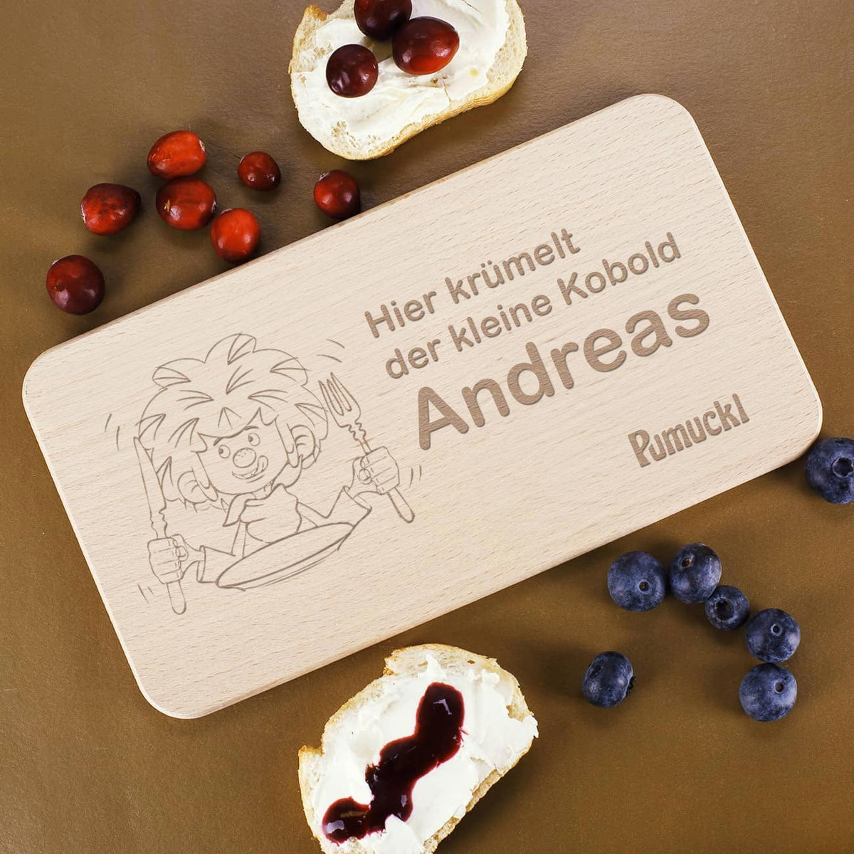 Pumuckl Frühstücksbrett aus Holz mit Wunschname Andreas, Kobold-Gravur und Snacks daneben.