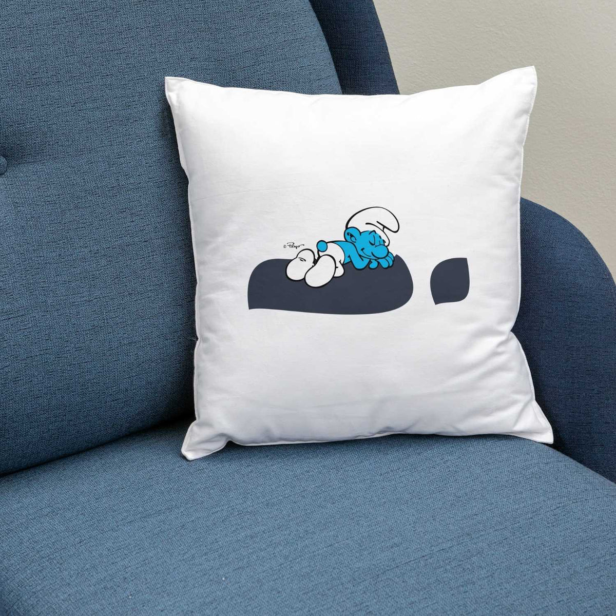 Weißes ®Die Schlümpfe Ausruhezeichen Kuschelkissen mit schlafendem Schlumpf-Motiv auf blauem Sessel