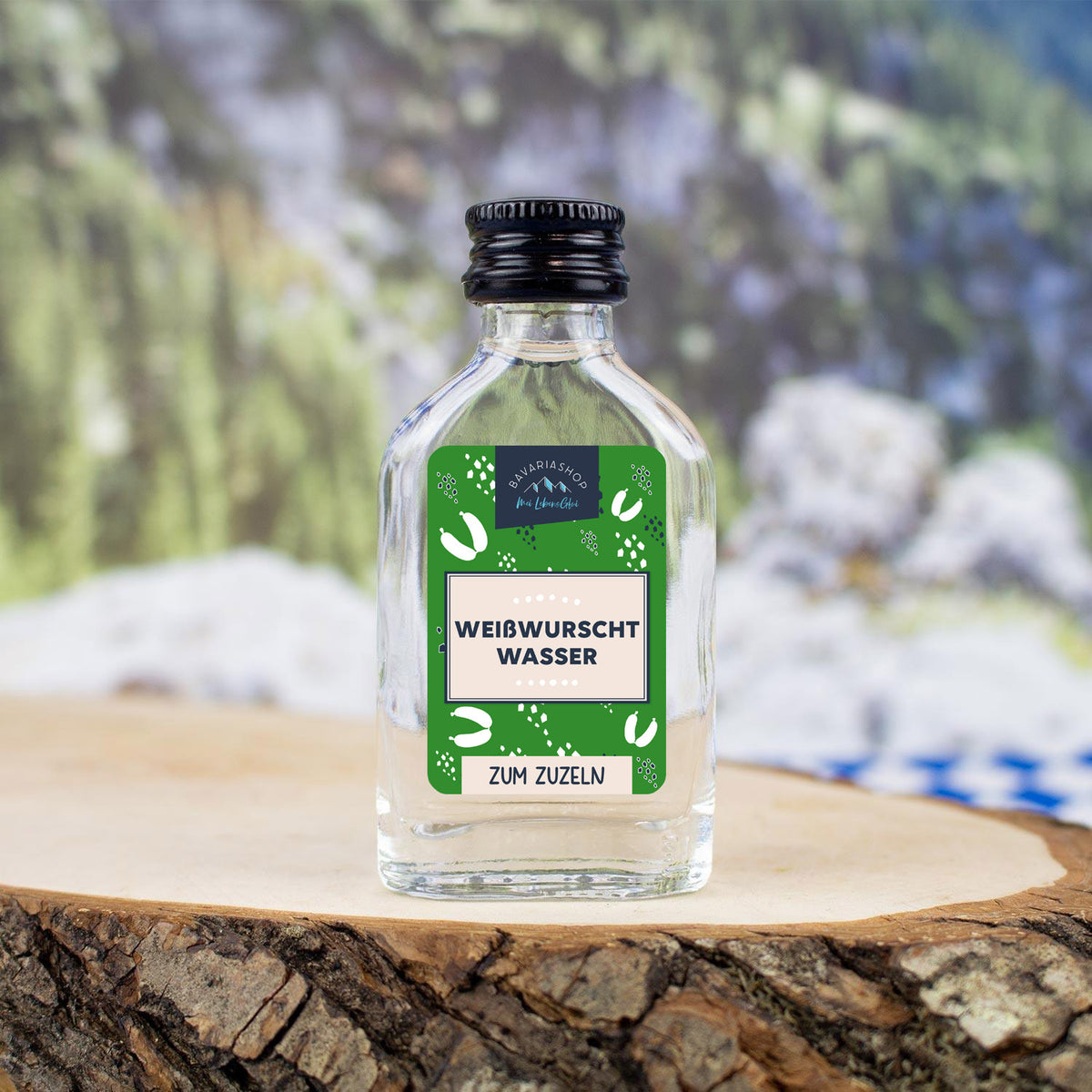 Klarer Obstler in transparenter Mini-Glasflasche mit bayrischem Etikett und Aufdruck „Weißwurschtwasser“, 2 cl.