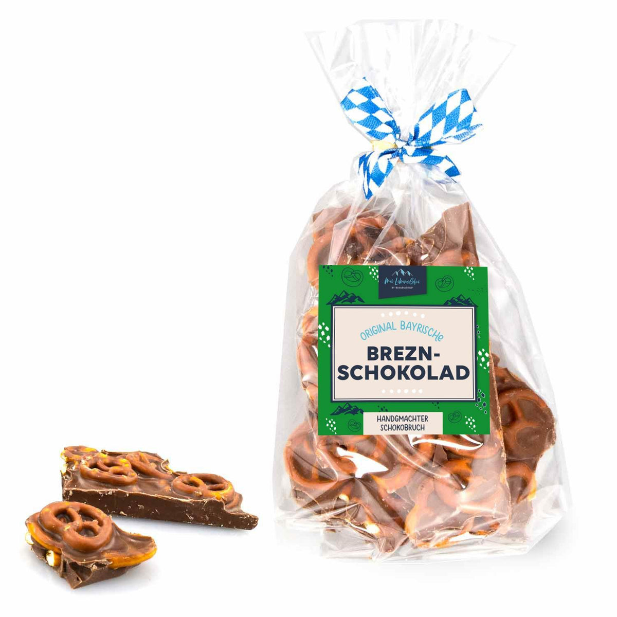 Schoko-Bruch mit Knusper-Brezn in transparenter Geschenktüte, blau-weiß karierter Schleife und Label. Einzelne Stücke liegen daneben.