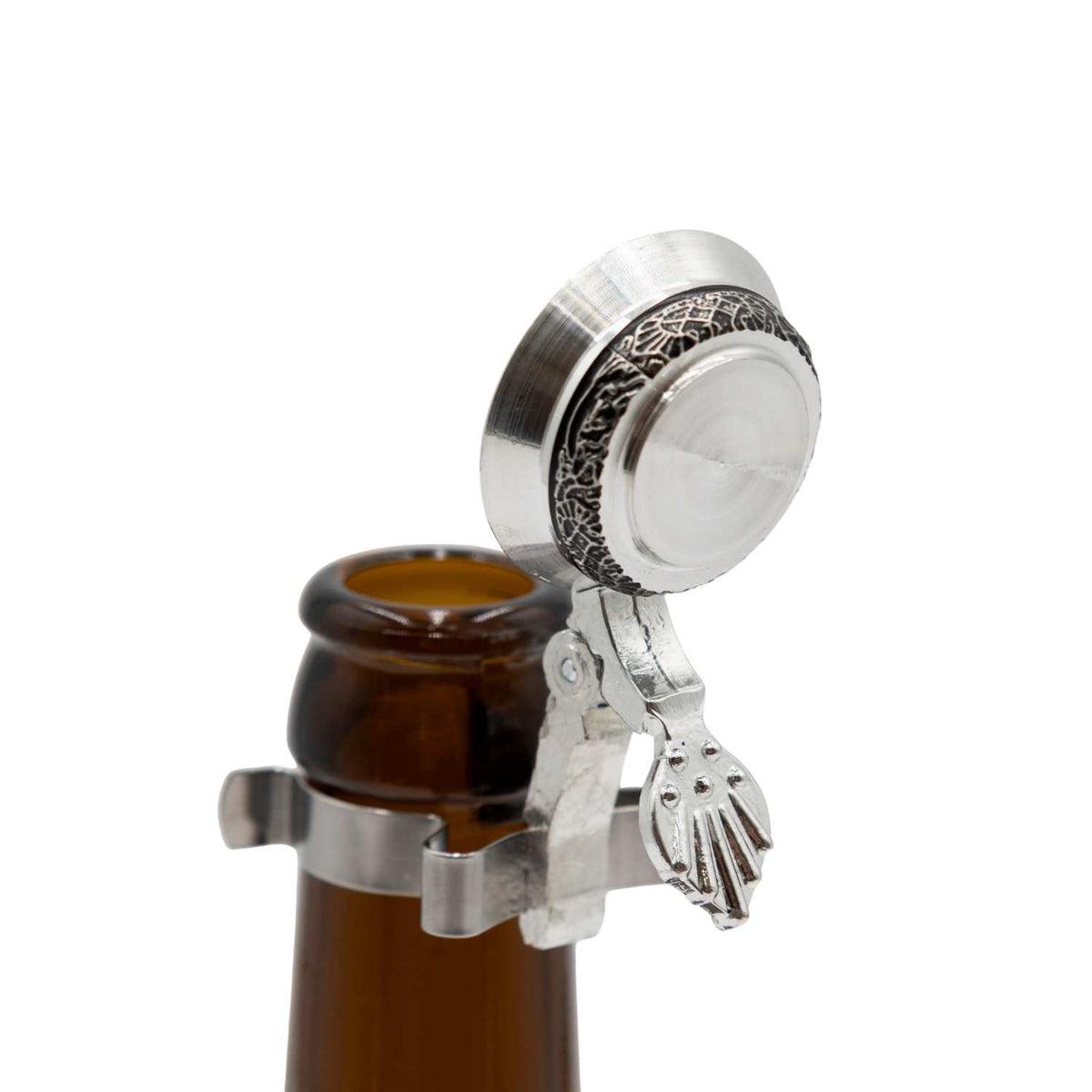 Silberner Bierflaschen Flachzinndeckel zum Aufstecken Ornamente mit filigranem Muster auf geöffneter brauner Bierflasche.