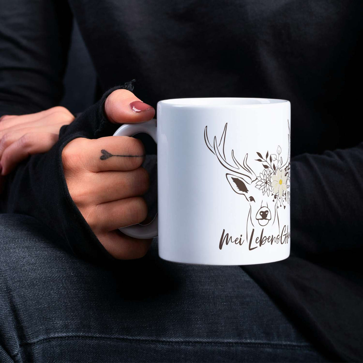 Kaffee Haferl Hirsch in Weiß mit detailliertem Hirschkopf und Blumenzeichnung, getragen von einer Person.