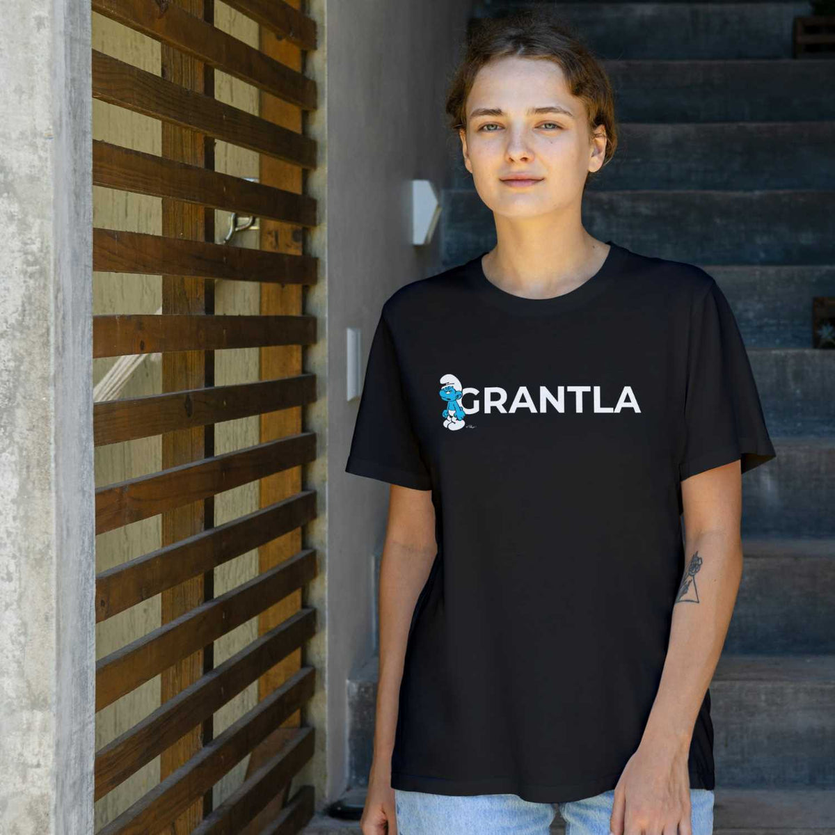 Junge Frau trägt schwarzes Damen T-Shirt Grantla von Die Schlümpfe, mit Griesgram Schlumpf Motiv.