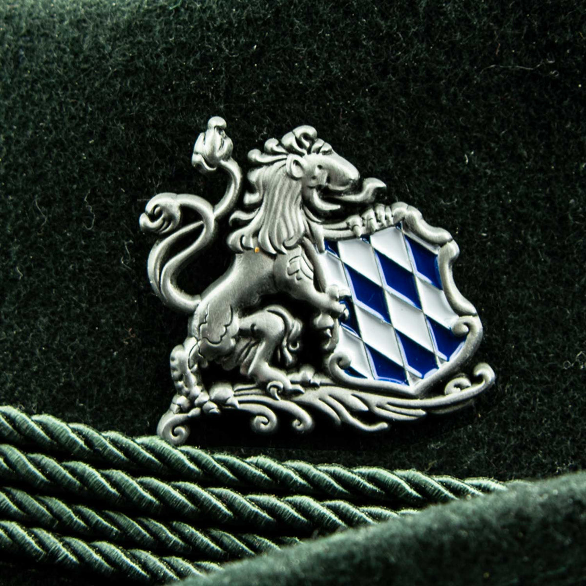 Dekorativer Pin Löwe mit Bayern Wappen auf Filzstoff. Detailansicht des traditionellen bayerischen Accessoires.