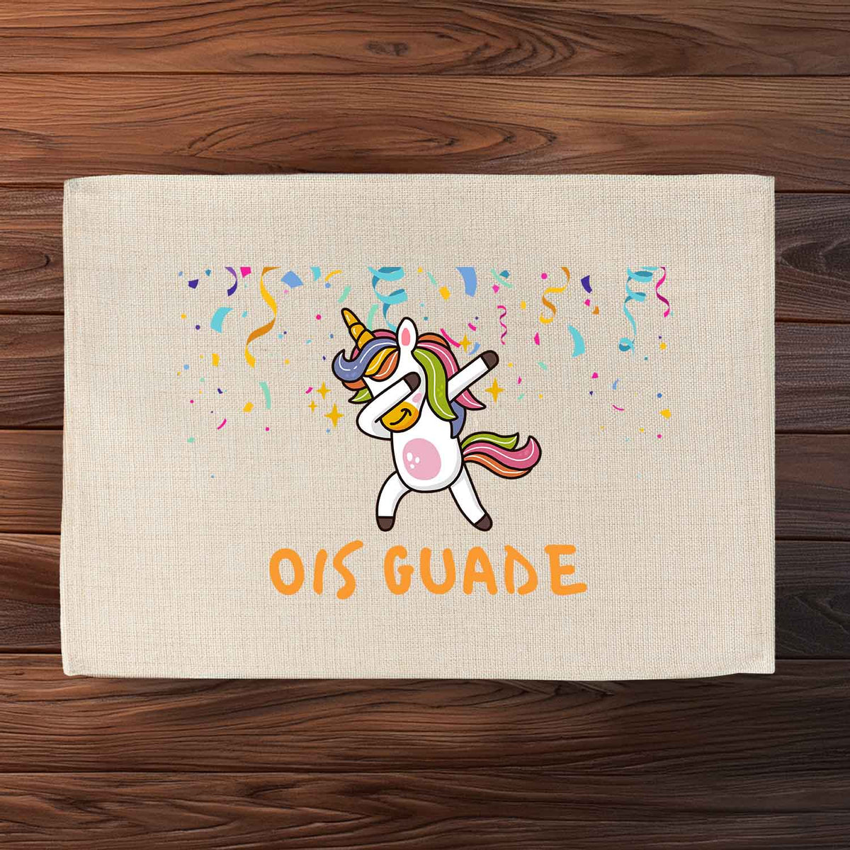 Tischset Ois Guade Einhorn mit dappendem Einhorn, Konfetti und buntem Schriftzug auf hellem Stoff.