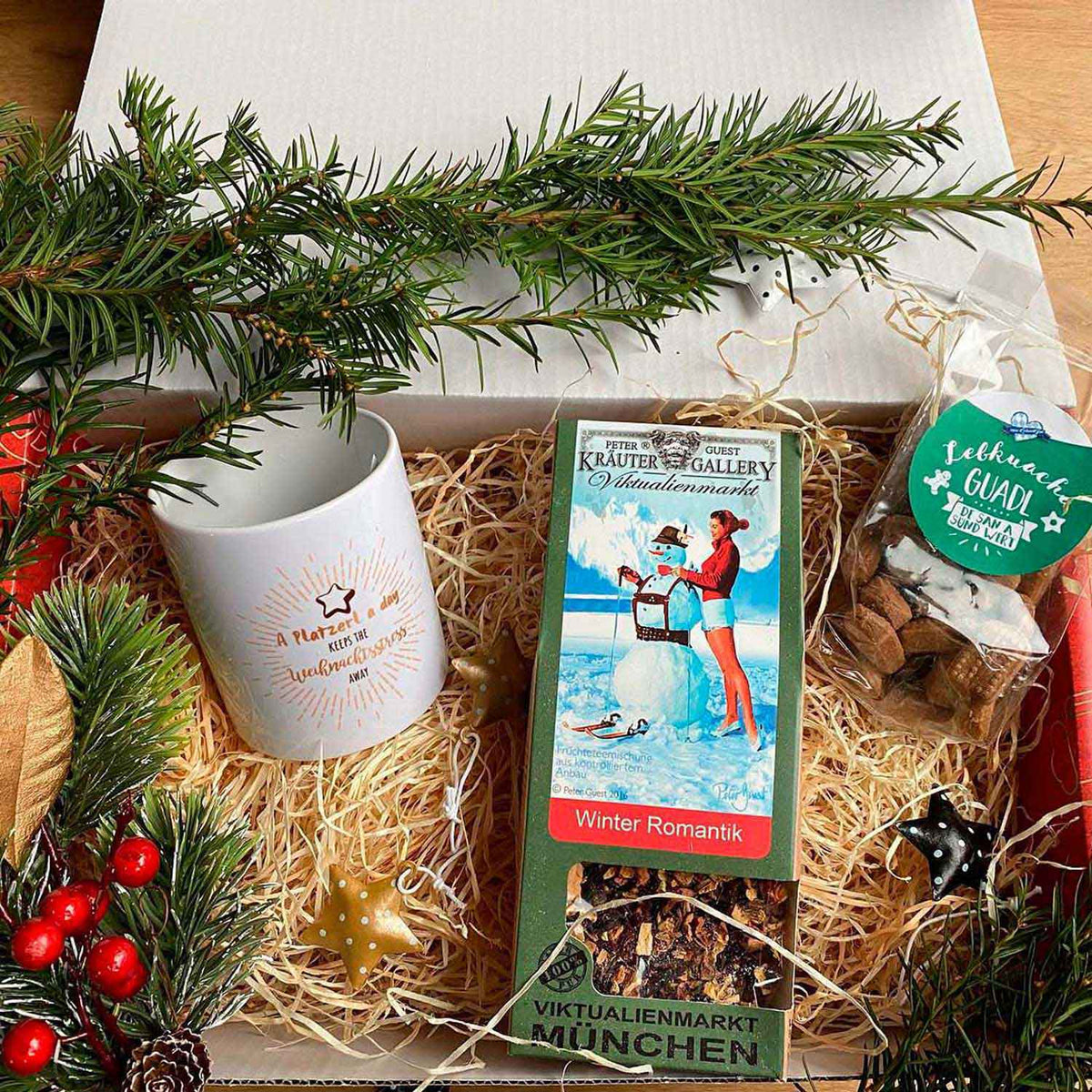Weihnachtliches Geschenkset mit Teetasse, Früchtetee, Lebkuchen Gudl und Tannenzweigen in Kisten-Präsentation.