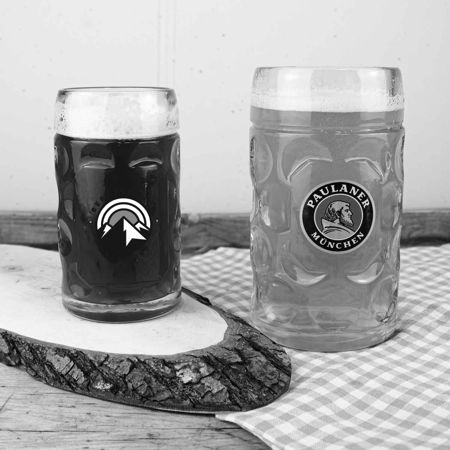 Zwei bauchige Bierkrüge mit Schaumkrone, gefüllt mit dunklem und hellem Bier, auf einem Holztisch.