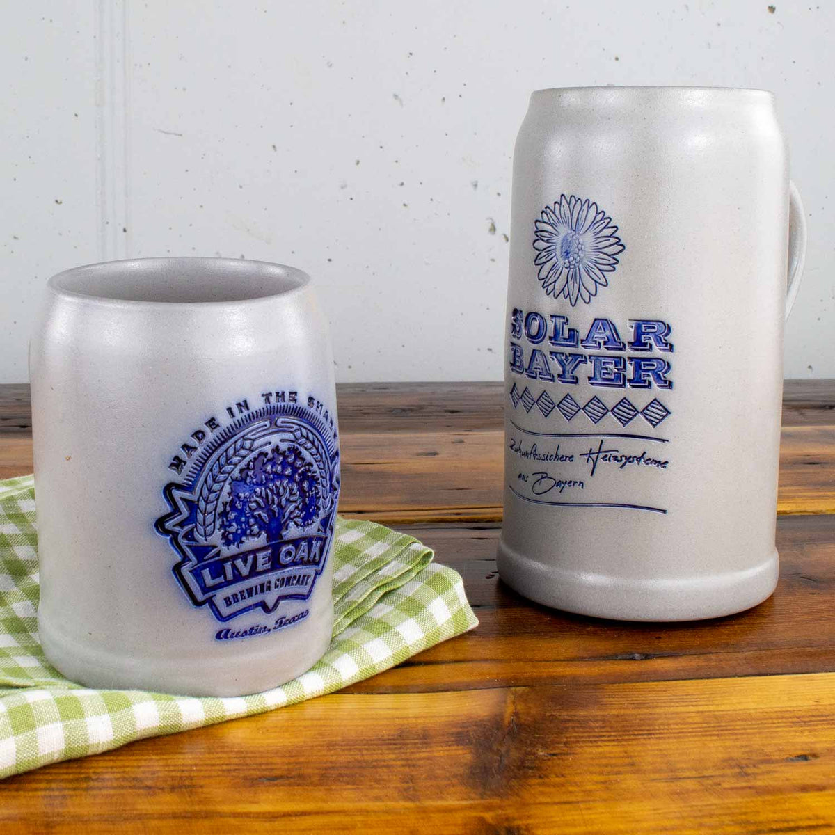 Zwei antike Salzglasur-Steinkrüge auf Holztisch, einer mit Live Oak Brewing Logo und der andere mit Solar Bayer Beschriftung.