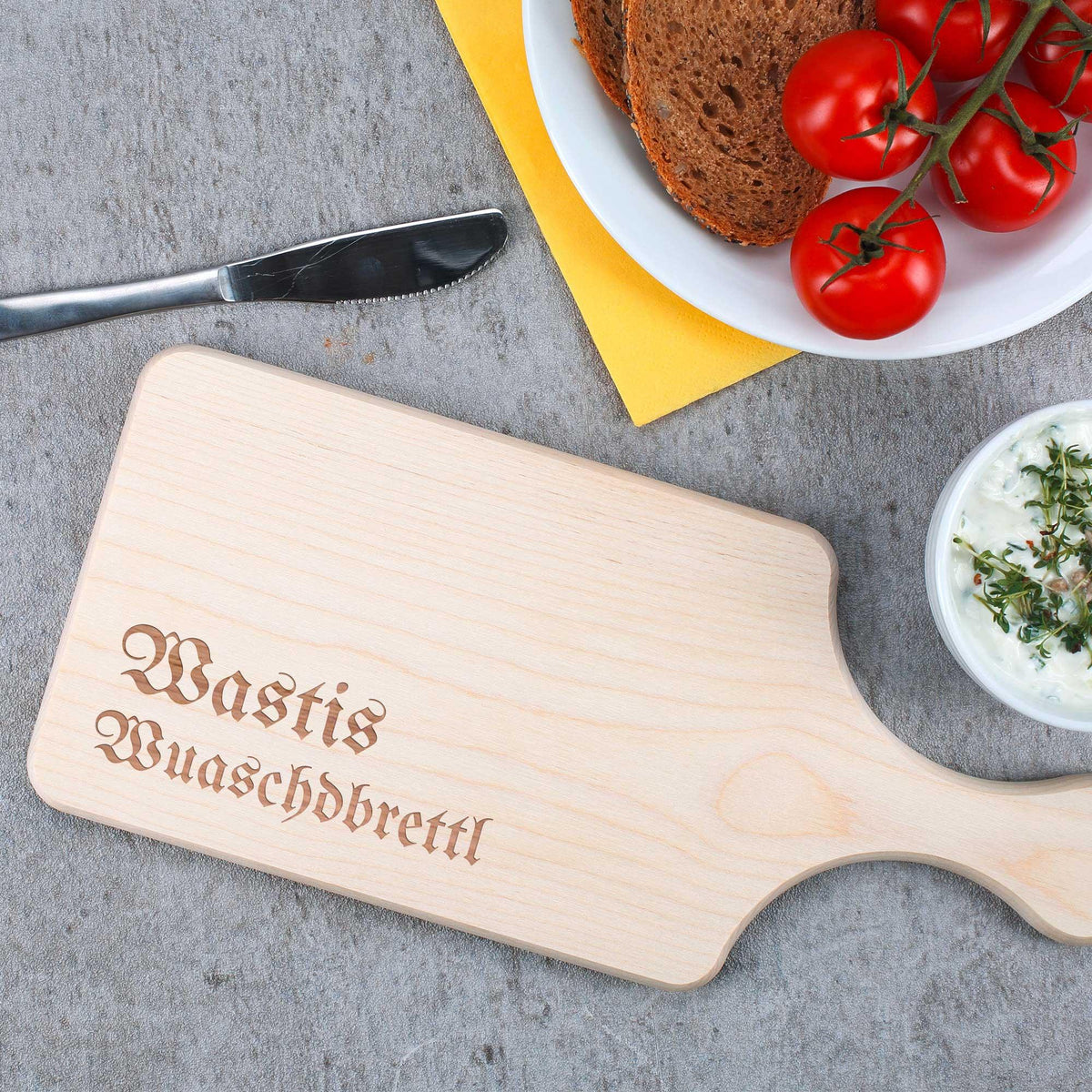 Personalisierte Brotzeitplatte aus hellbraunem Holz mit Gravur, dazu frische Tomaten, Brot und Dip.