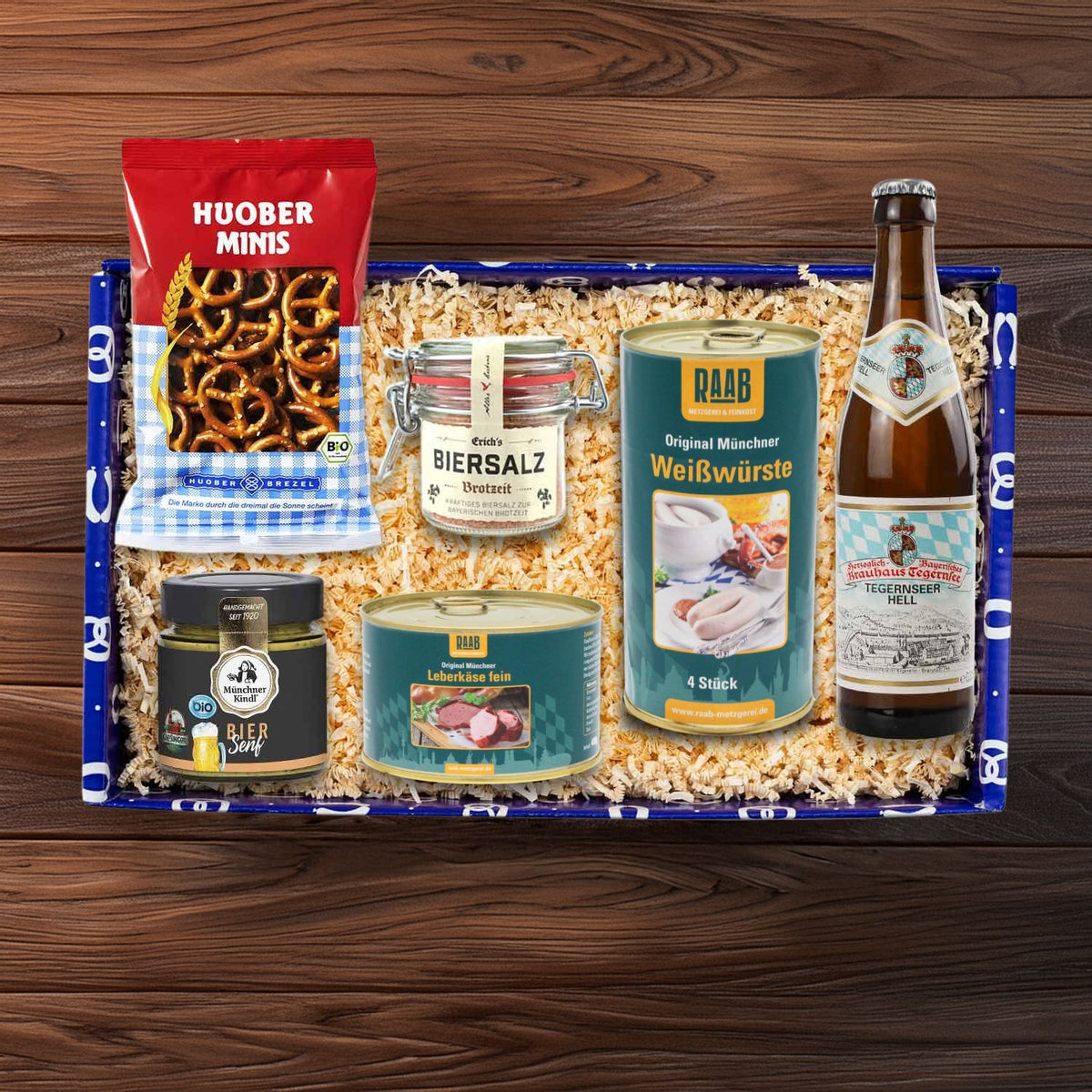 Blaue Geschenkbox "Brotzeit" mit Brezeln, Biersalz, Weißwürsten, Leberkäse, Biersenf und Tegernseer Bier.