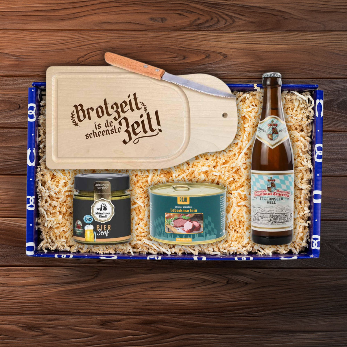 Geschenkbox mit Leberkäse, Bier, süßem Senf, Brotzeitbrett und Messer für bayerischen Genuss.