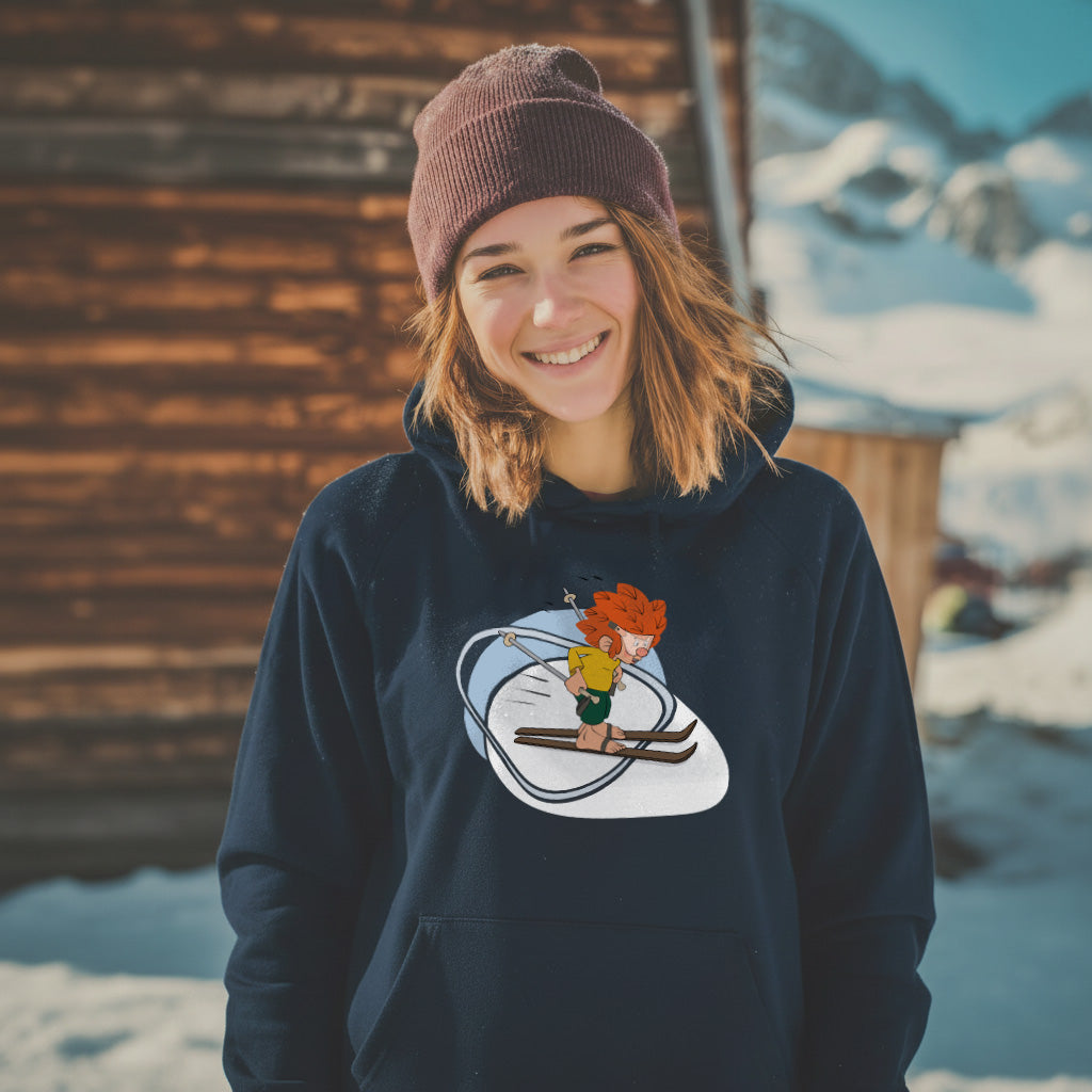 Lachende Frau im dunkelblauen Pumuckl Hoodie „Skifahren“ vor einer Berghütte im Schnee