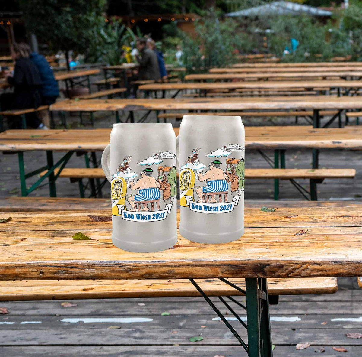Zwei Koa Wiesnkrug 2021 Bierkrüge mit Karikaturen auf Holztischen im Biergarten für Oktoberfest-Fans