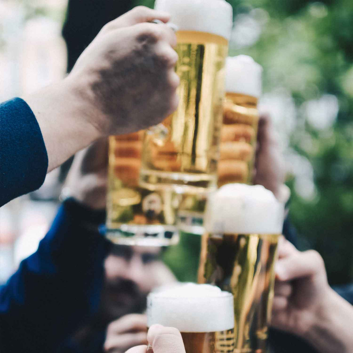 Frohe Menschen stoßen mit gut gefüllten Bierkrügen und Gläsern in Feierlaune an.