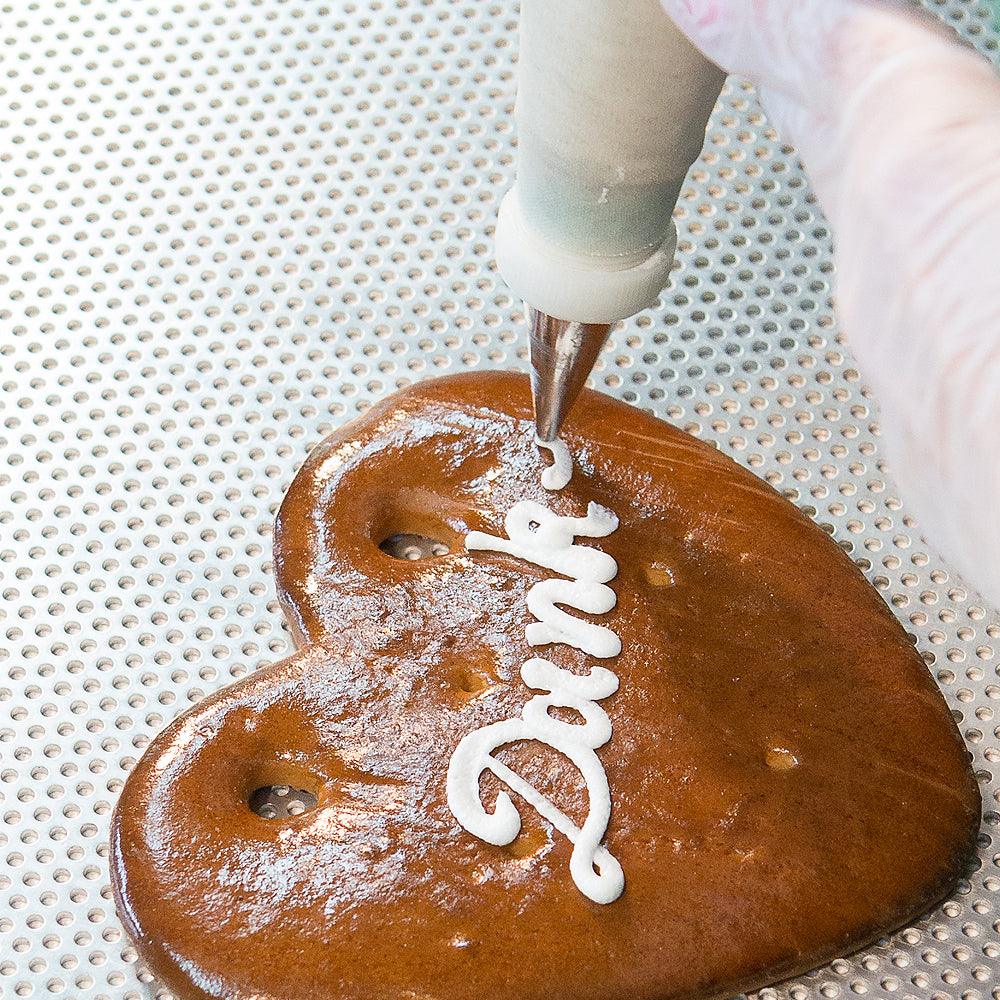 Lebkuchenherz mit weißer Zuckerguss-Aufschrift "Dankeschön", dekoriert mit Spritzbeutel.
