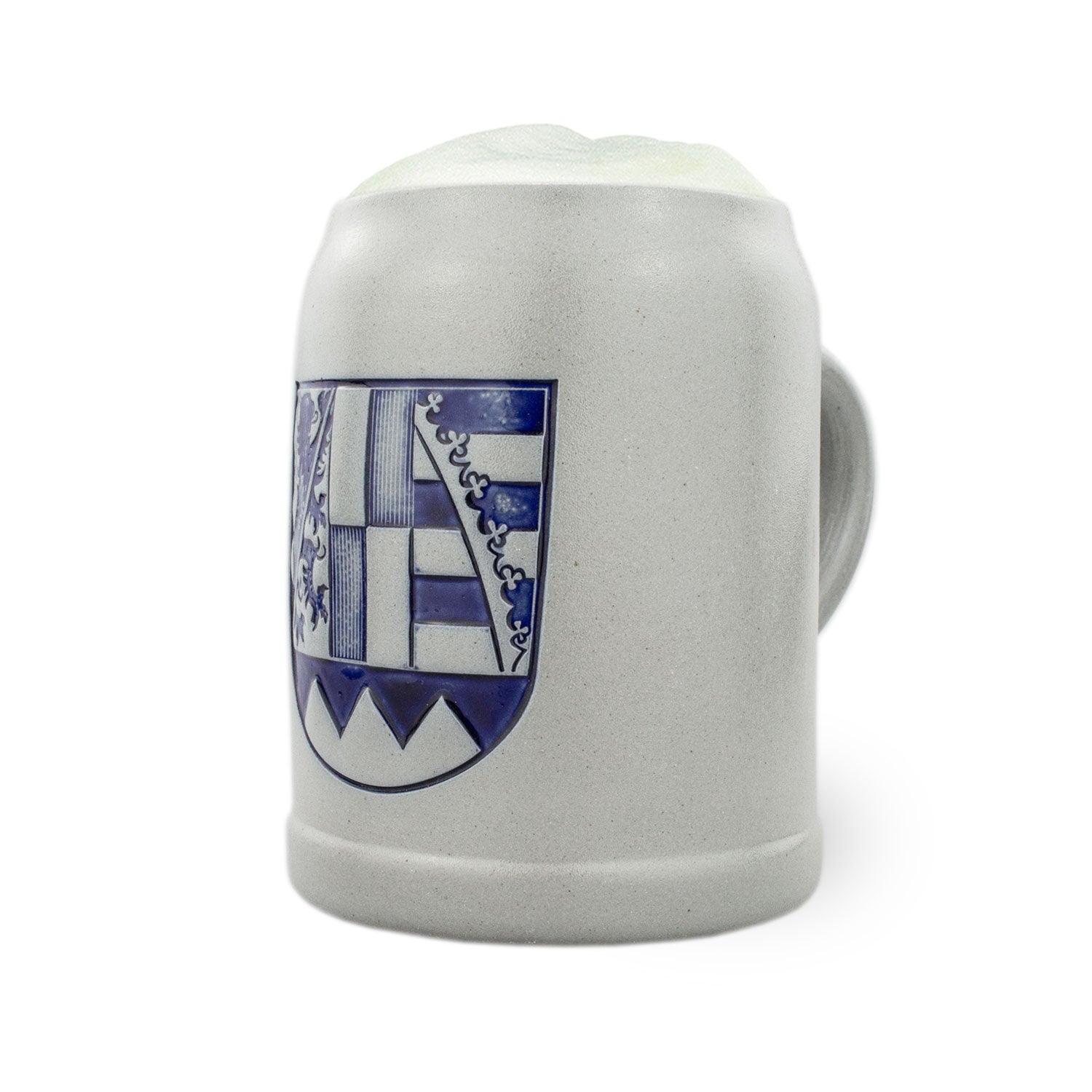 PREMIUM Bierkrug Oberfranken aus grauem Steingut mit blauem Wappen und gefüllt mit Bierschaum.