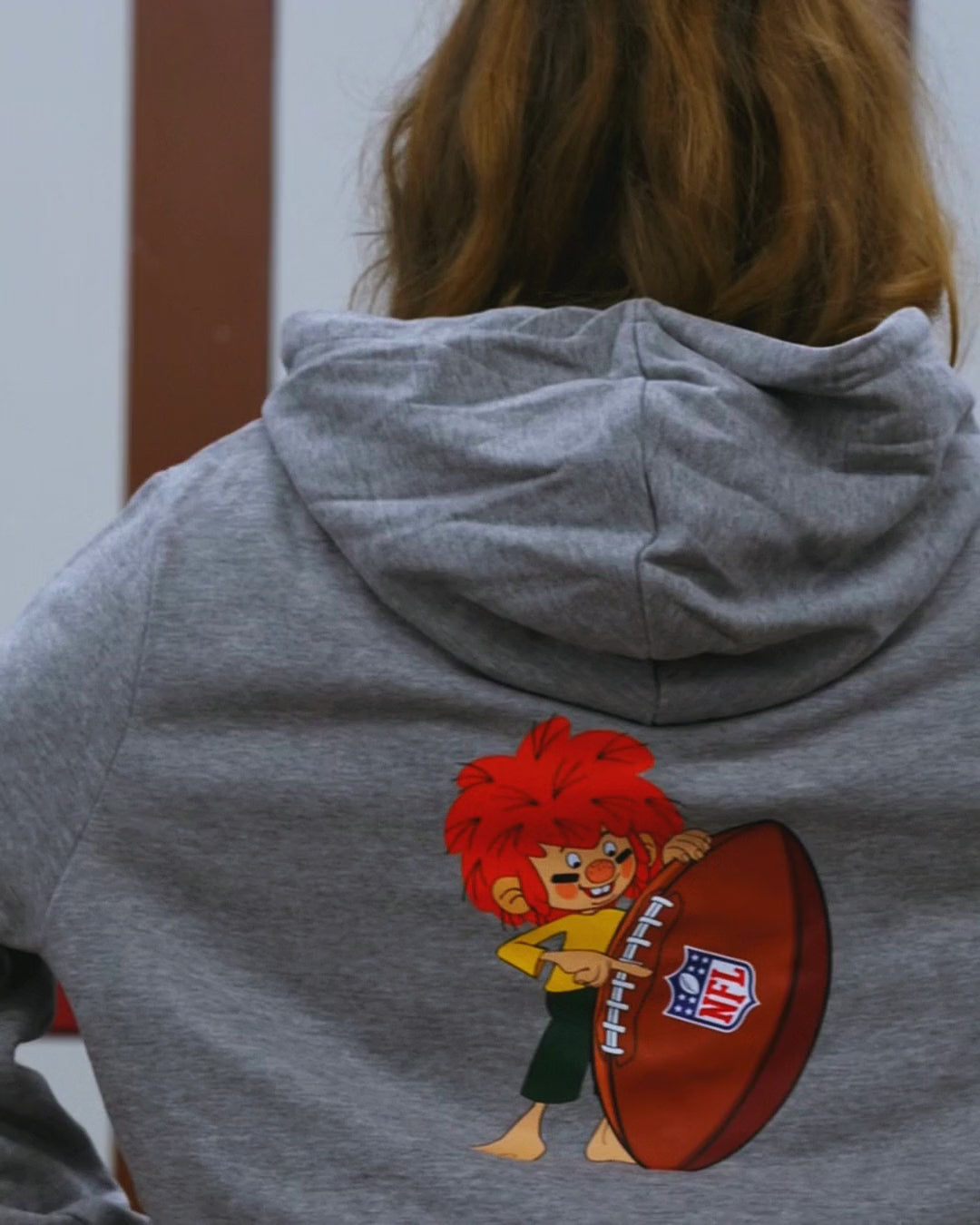 NFL x Pumuckl Hoodie Football in Grau – Vorderseite mit NFL-München-Logo und Rückseite mit Pumuckl und Football