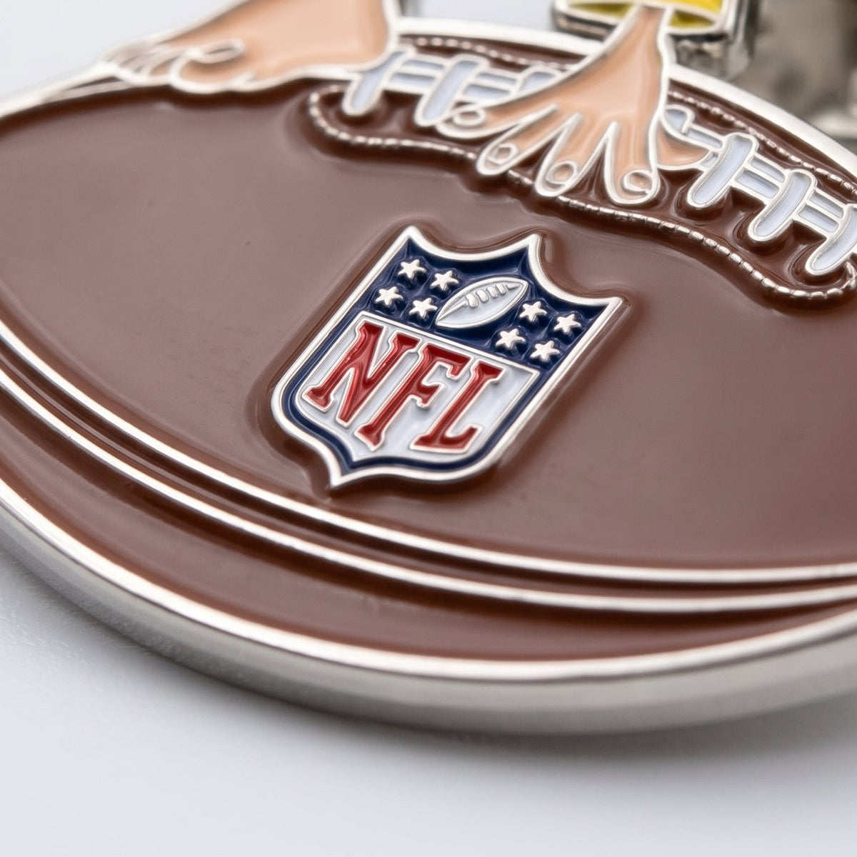 Detailaufnahme NFL x Pumuckl Pin Touchdown – erhabene Metallstege, glänzende Emaille und NFL-Logo auf dem Football
