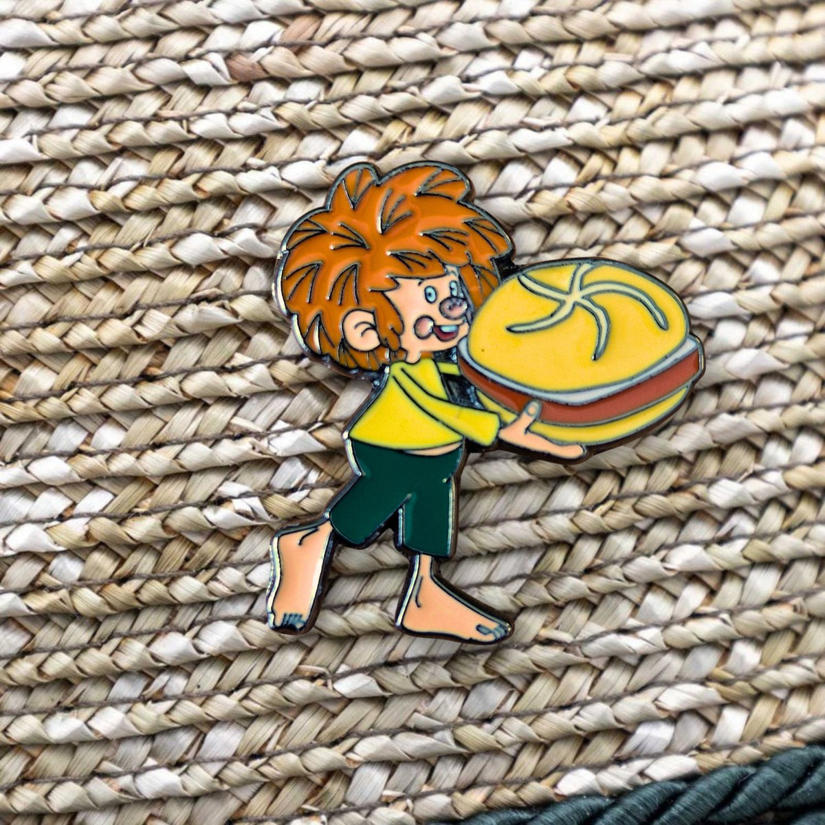 Pumuckl Pin mit rotem Haar und bayerischer Leberkassemmel auf geflochtenem Untergrund