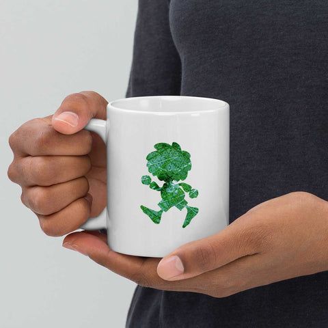 Person hält weiße ®Pumuckl Tasse Ampel-Edition mit grünem Kobold-Muster.