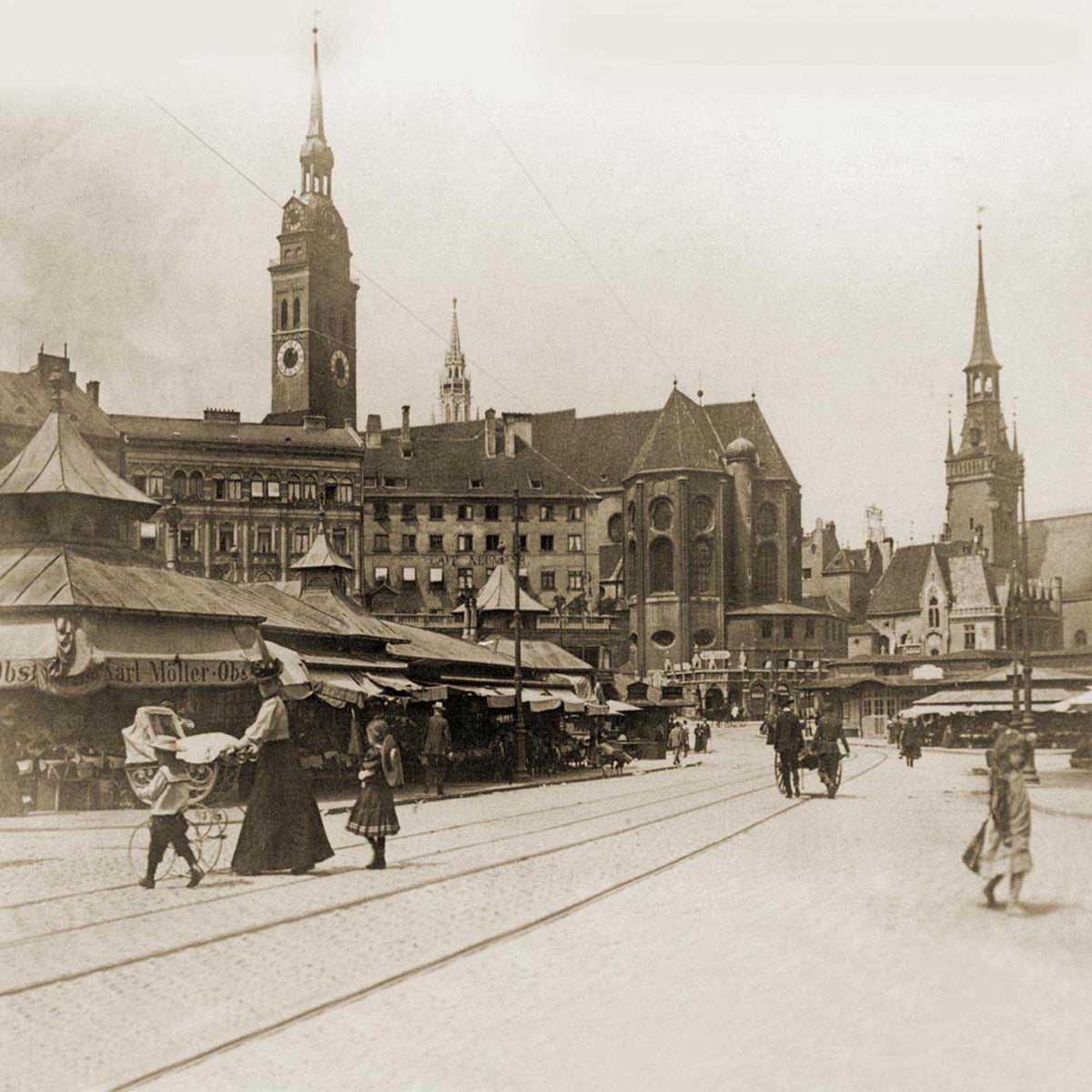 Historische Schwarz-Weiß-Ansicht einer belebten Straße mit Fußgängern, Kutsche, Marktständen und Kirchtürmen.