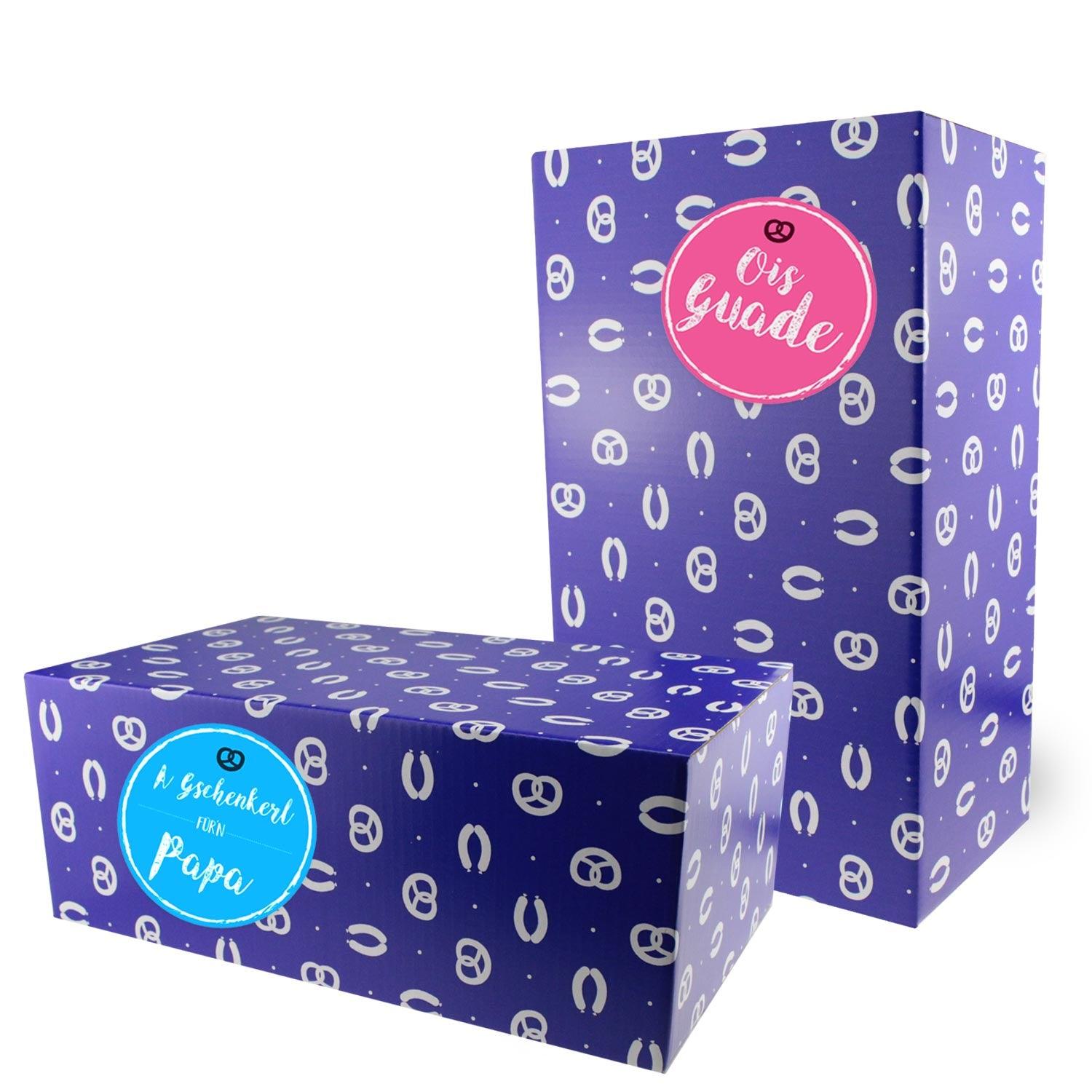 Zwei lilafarbene Geschenkboxen mit Brezelmuster, eine mit rosa Etikett Ois Guade, die andere mit blauem Aufkleber für Papa.